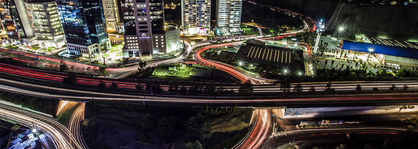 Imagen aérea nocturna de glorieta vehicular, autos en movimiento, luces rojas barridas